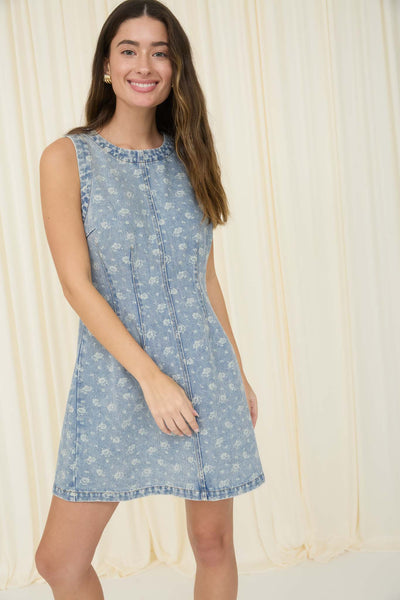 Woman wearing a light blue floral dress against a beige curtain background