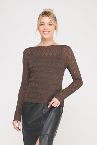 Woman wearing a brown, lace, long-sleeve top with a black leather skirt on a white background