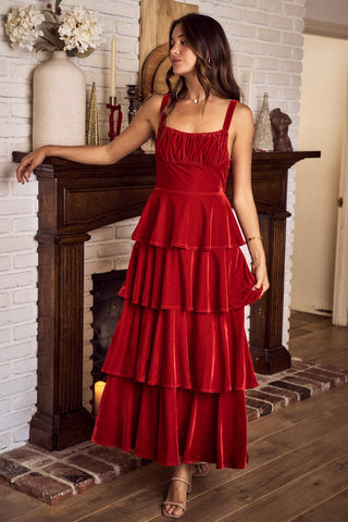 Woman in a red dress standing in a room with a fireplace.