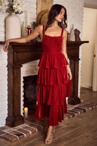 Woman in a red dress standing in a room with a fireplace.