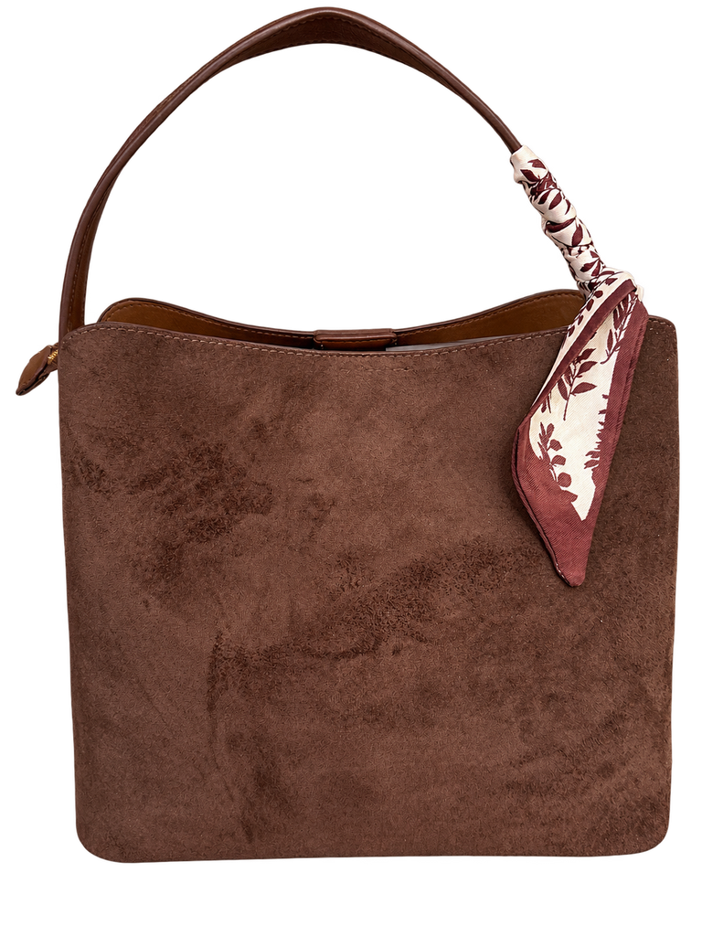 Brown suede shoulder bag with a curved leather handle and a burgundy-and-cream floral scarf tied around the handle.