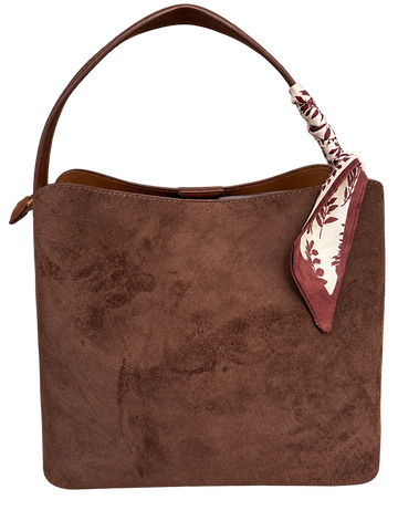 Brown suede shoulder bag with a curved leather handle and a burgundy-and-cream floral scarf tied around the handle.