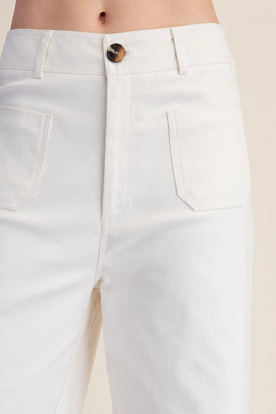 Woman wearing white wide-leg pants against a plain background