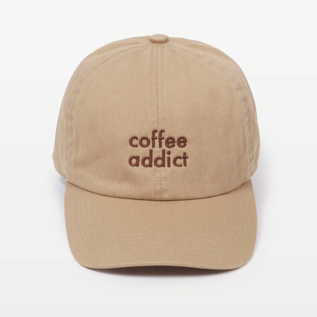 Sandy beige baseball cap with 'coffee addict' embroidered in brown on the front, against a plain background