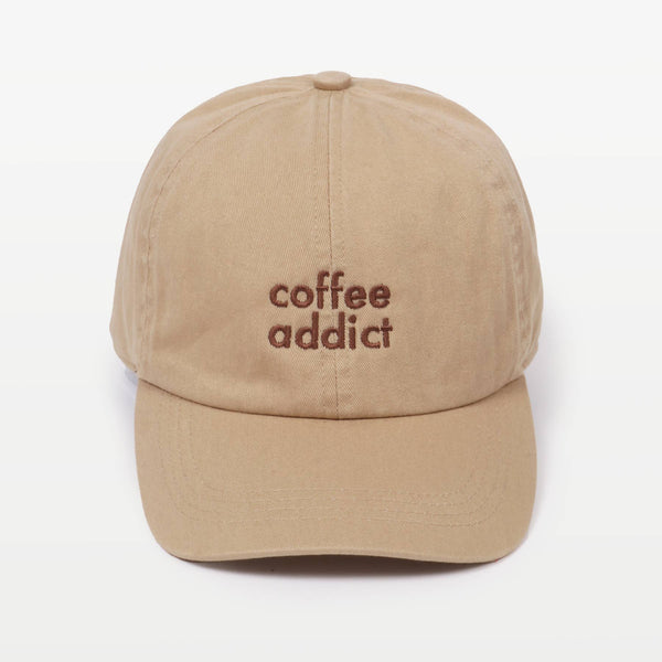 Sandy beige baseball cap with 'coffee addict' embroidered in brown on the front, against a plain background