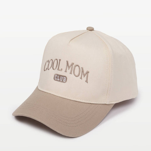 Two-toned baseball cap in cream and beige featuring the embroidery "COOL MOM CLUB" against a plain background
