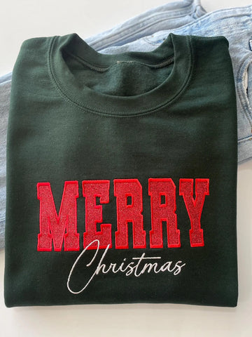 A dark green-colored crewneck sweatshirt featuring 'MERRY Christmas' printed on the front, with 'MERRY' in glittery red block letters and 'Christmas' in white cursive script