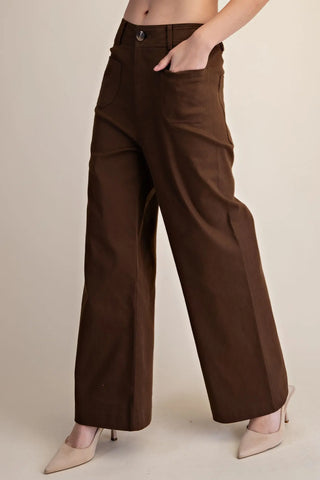 Woman wearing dark brown wide-leg pants against a plain background