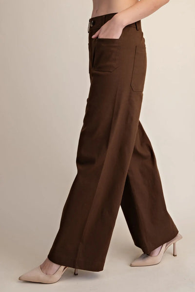 Woman wearing dark brown wide-leg pants against a plain background