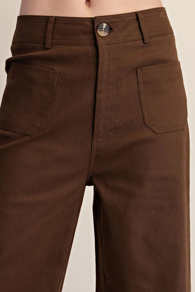 Woman wearing dark brown wide-leg pants against a plain background