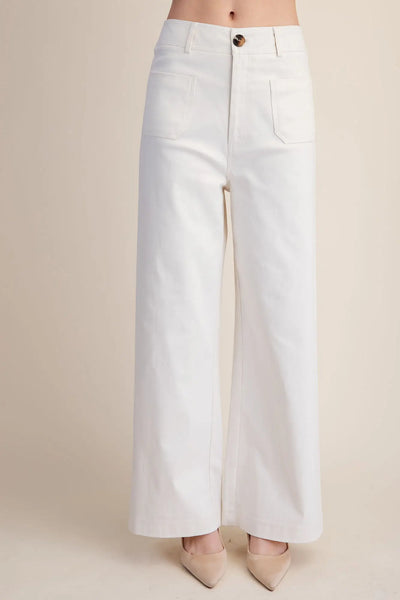 Woman wearing white wide-leg pants against a plain background