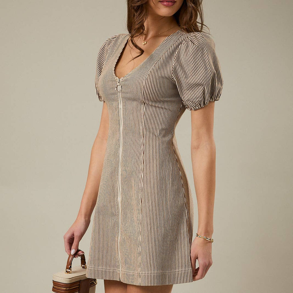 Woman wearing a beige and brown vertically striped mini dress with puff sleeves, a V-neckline, and a front "O" shaped zipper. It is styled with a small handbag