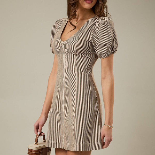 Woman wearing a beige and brown vertically striped mini dress with puff sleeves, a V-neckline, and a front "O" shaped zipper. It is styled with a small handbag