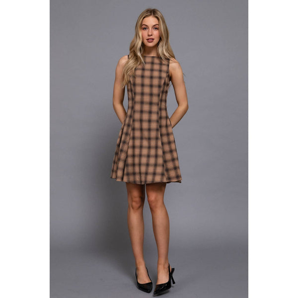 Woman wearing a tan, sleeveless, plaid, swing dress in a neutral background
